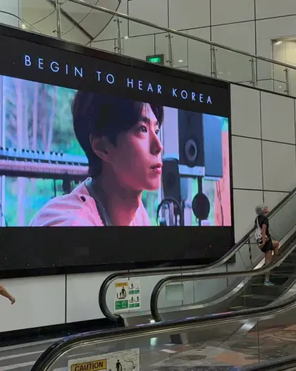 Begin to Hear Korea campaign on a large indoor LED screen beside escalators in Singapore