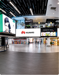 Huawei and fashion ads on large LED screens in a shopping mall concourse