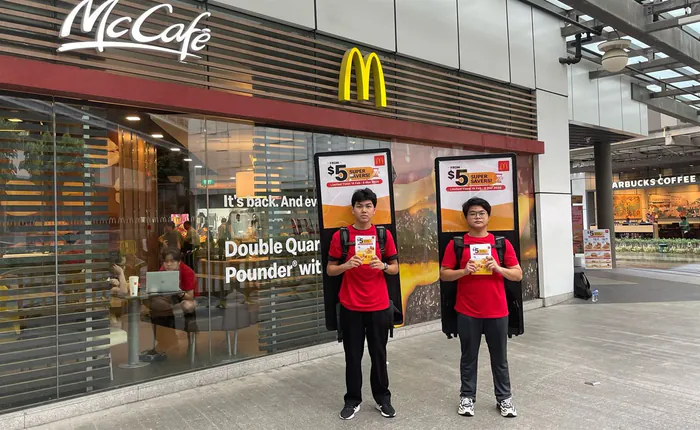 Two PosterWalker™ talents carrying McDonald’s lightbox displays outside a McCafé in Singapore